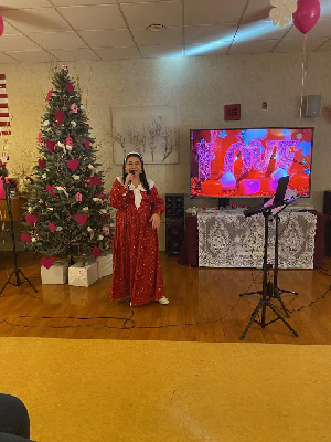 Woman singing in front of Christmas tree